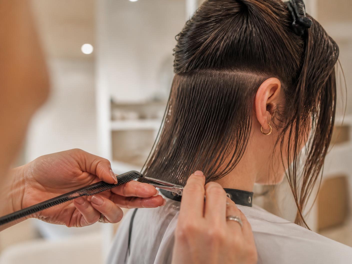 Friseurin schneidet mittellanges Haar einer Kundin im Salon in Wuppertal